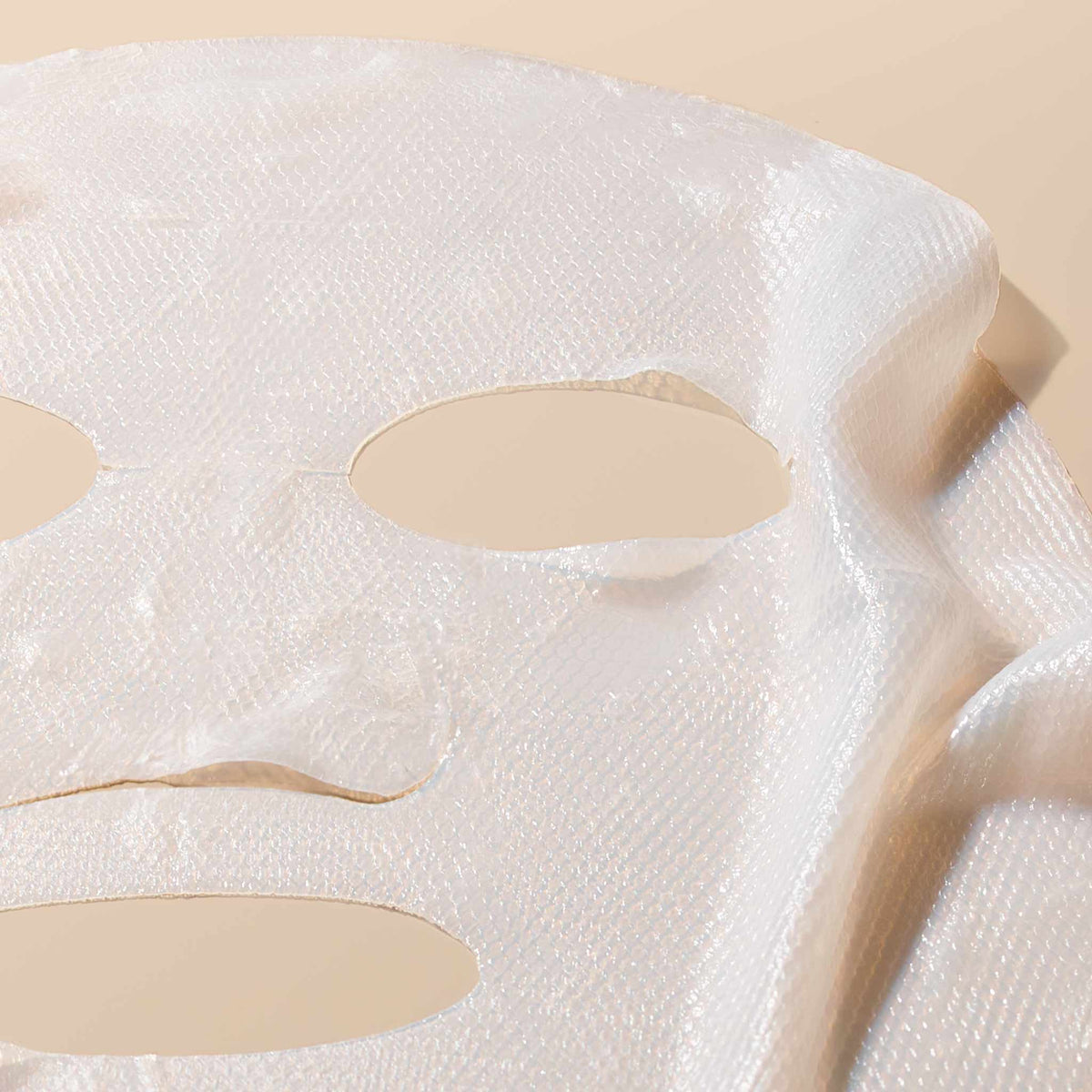 A white, textured Lune+Aster 5 Minute Rescue Mask Calm with cutouts for eyes and a mouth, designed to reduce the appearance of aggravated skin.