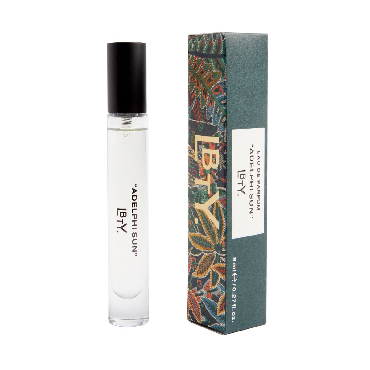 A sunlit cylindrical glass Adelphi Sun Eau De Parfum rollerball with a black cap sits next to its tall, rectangular patterned box.