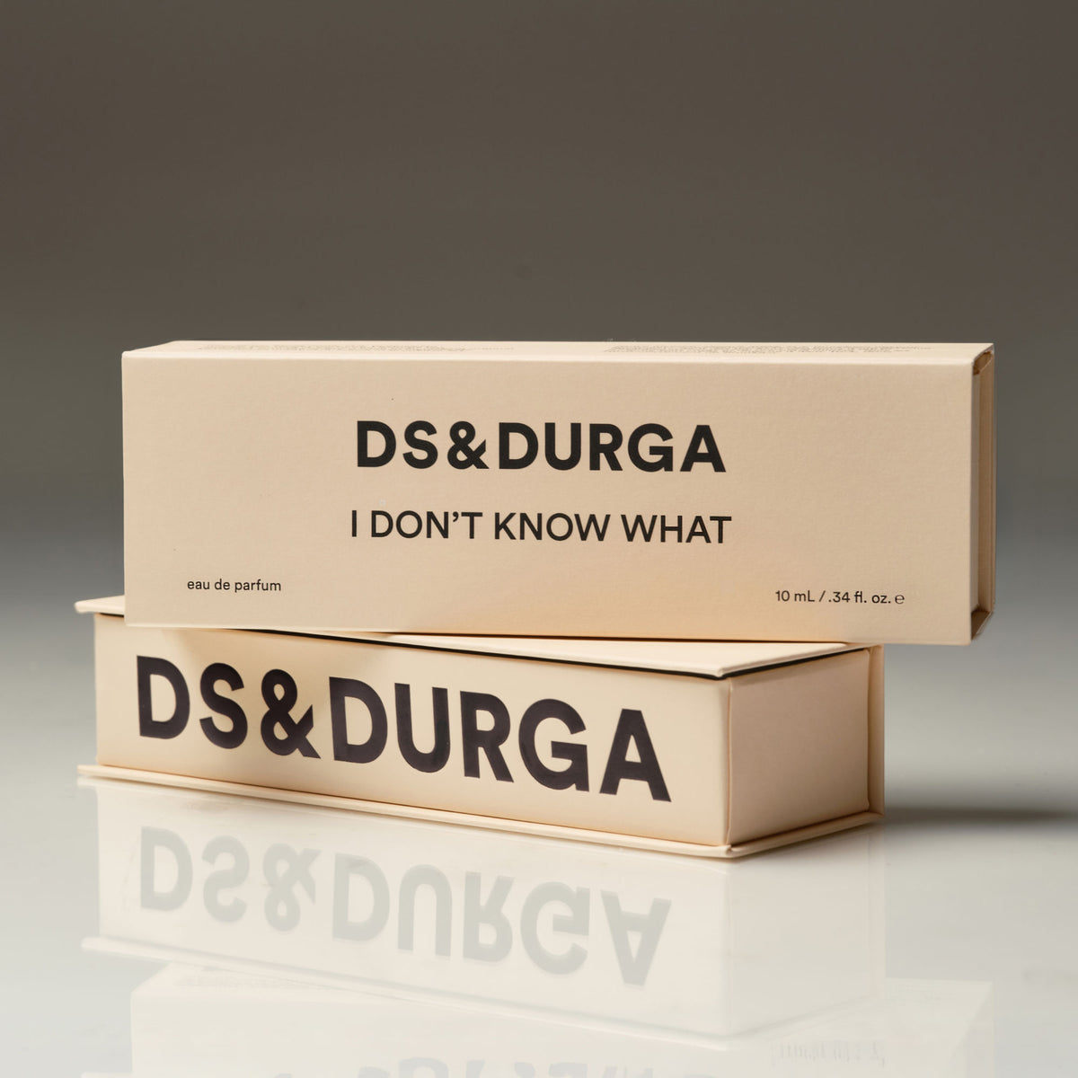 Two cream-colored transparent D.S. & Durga I Don’t Know What Eau de Parfum boxes stacked on a reflective surface, with the brand and product names printed in black text.