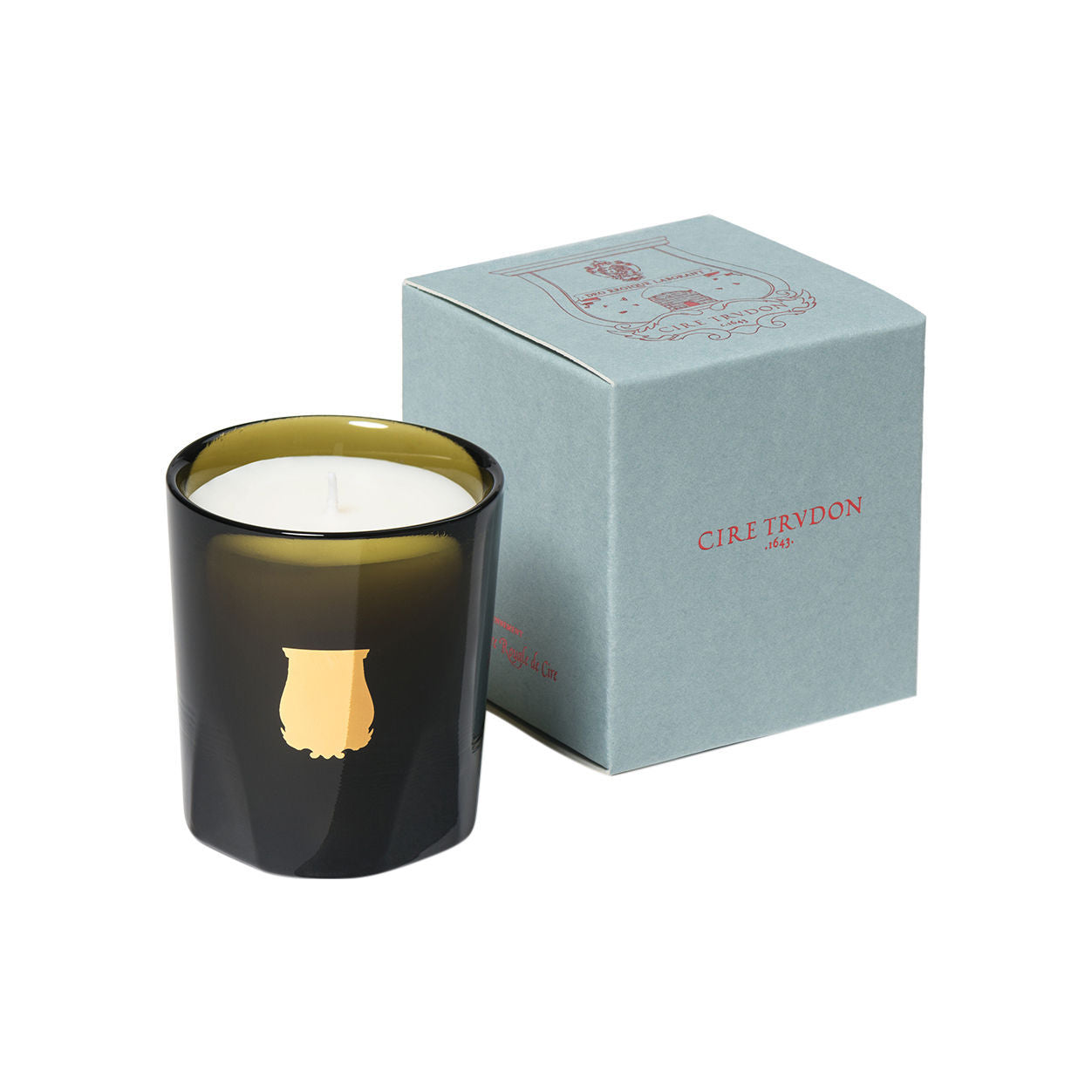 Abd El Kader scented candle in a dark glass vessel with a gold emblem, standing next to its light blue cardboard box.