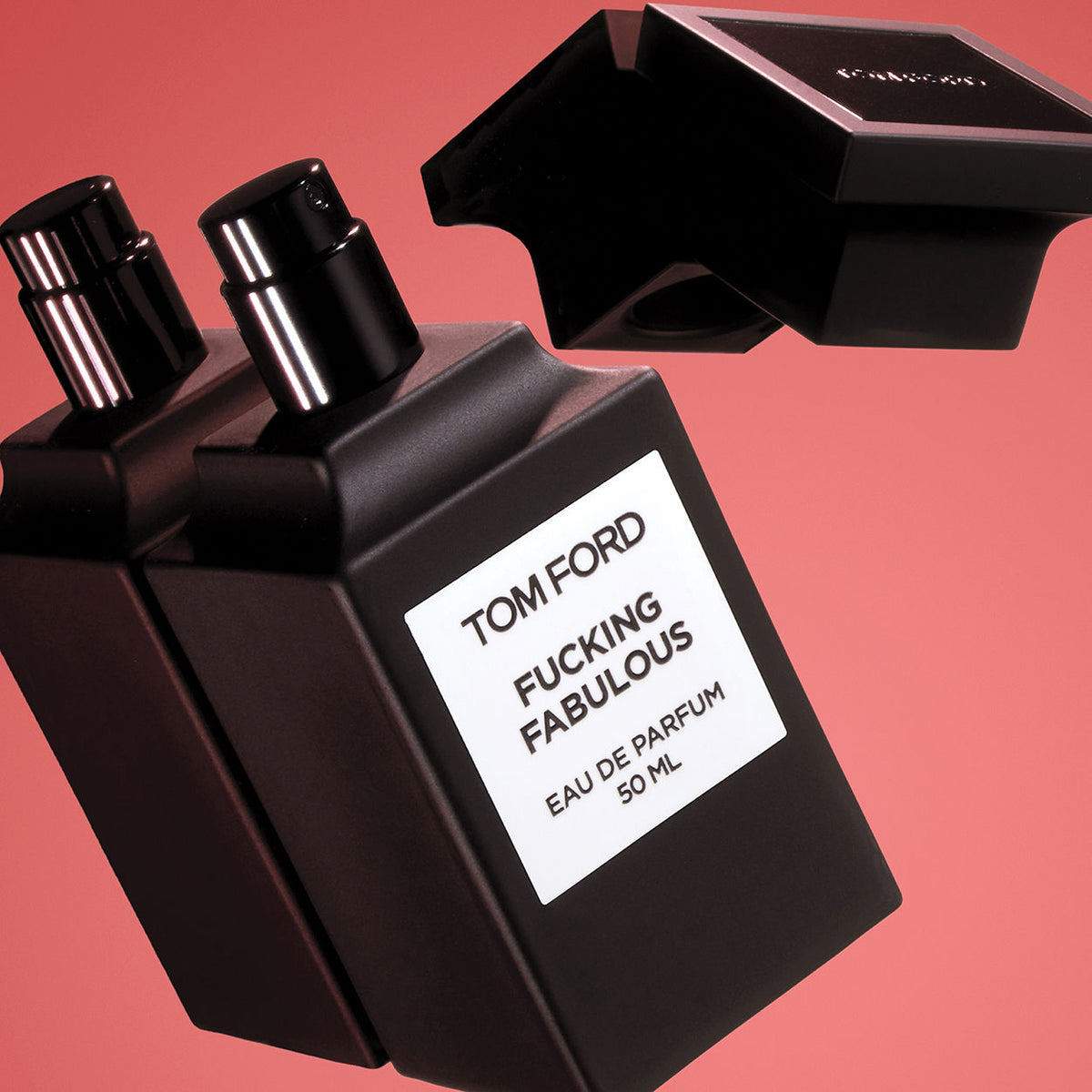 A matte black bottle of Tom Ford F’ing Fabulous Eau de Parfum Spray with a detached cap floating above it, featuring a white label with black text on a pink background.