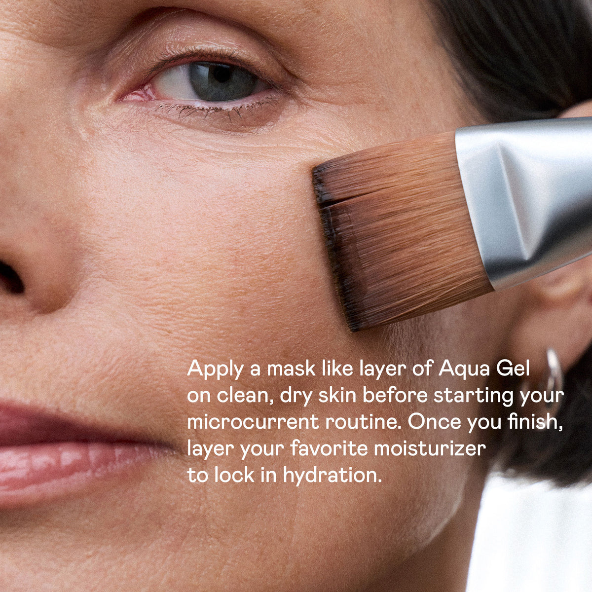 A brush applying NuFace Aqua Gel Hydrating Microcurrent Activator with Hyaluronic Acid to a cheek, with text instructing users to apply a mask-like layer before their microcurrent routine and follow with moisturizer.