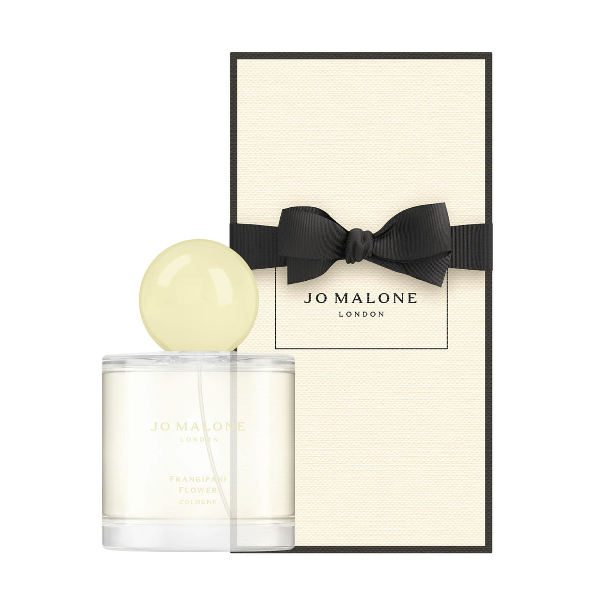 A cylindrical Jo Malone London Frangipani Flower Cologne bottle with a round pale yellow cap stands in front of a rectangular cream-colored gift box tied with a black ribbon.