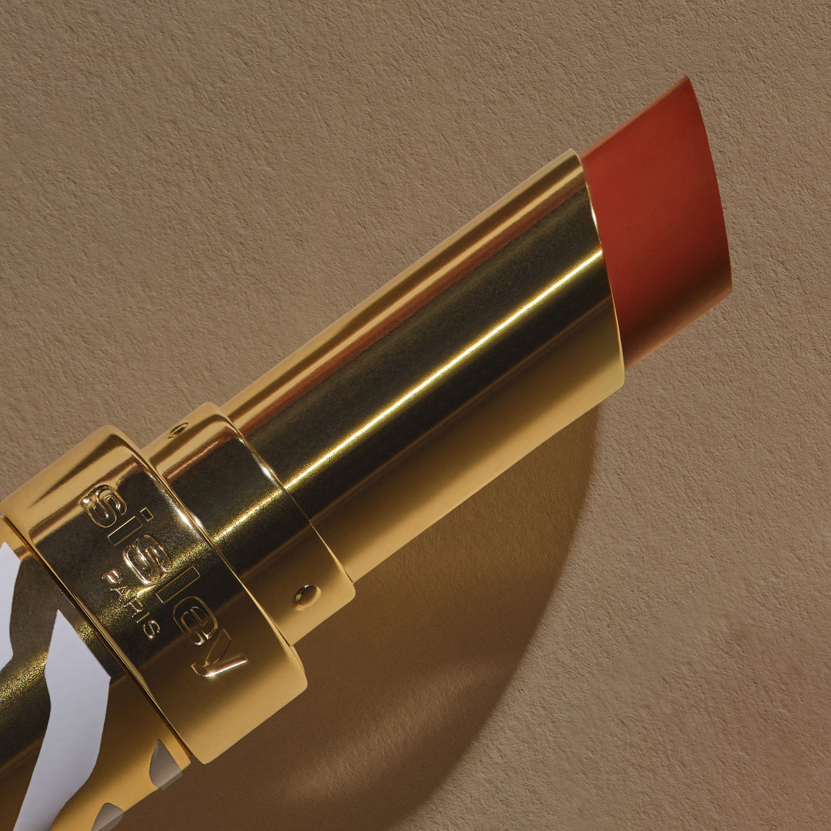 A gold tube of Phyto-Rouge Shine lipstick with an extended coral-toned bullet that offers a balm-like sensation.