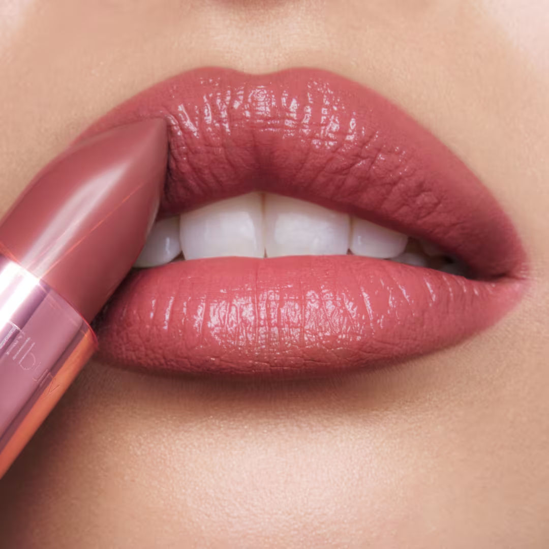 Close-up of a dusty rose K.I.S.S.I.N.G. Lipstick being applied to lips for a satin shine.