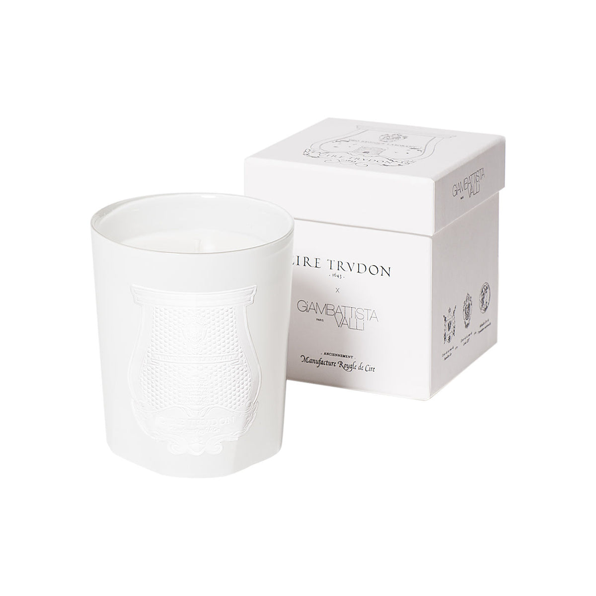 A white Trudon Giambattista Valli Candle in an embossed glass vessel next to its matching white square box.