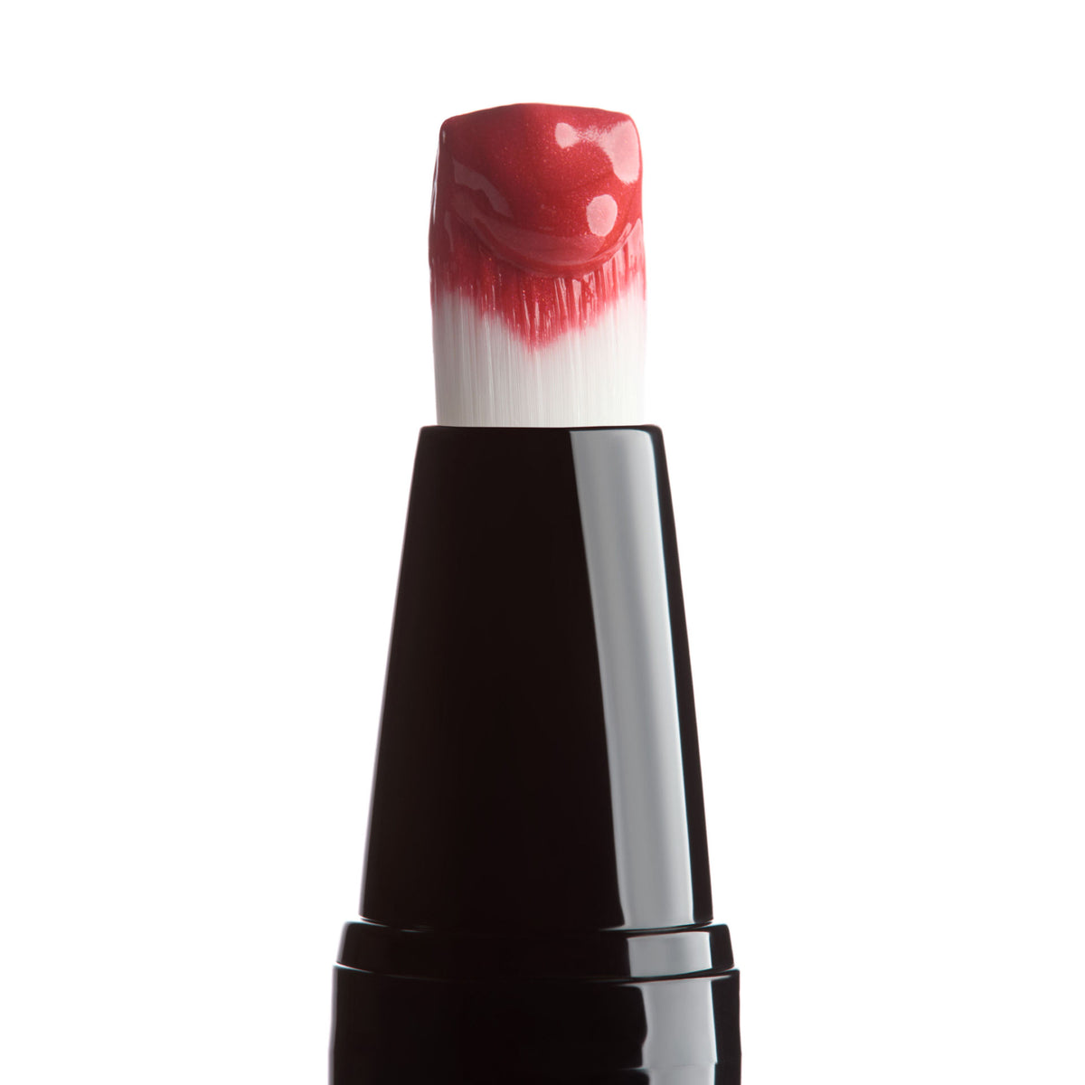 A close-up of a cosmetic brush tip coated in a dollop of glossy, long-wearing red Trish McEvoy Liquid Face Color gel.
