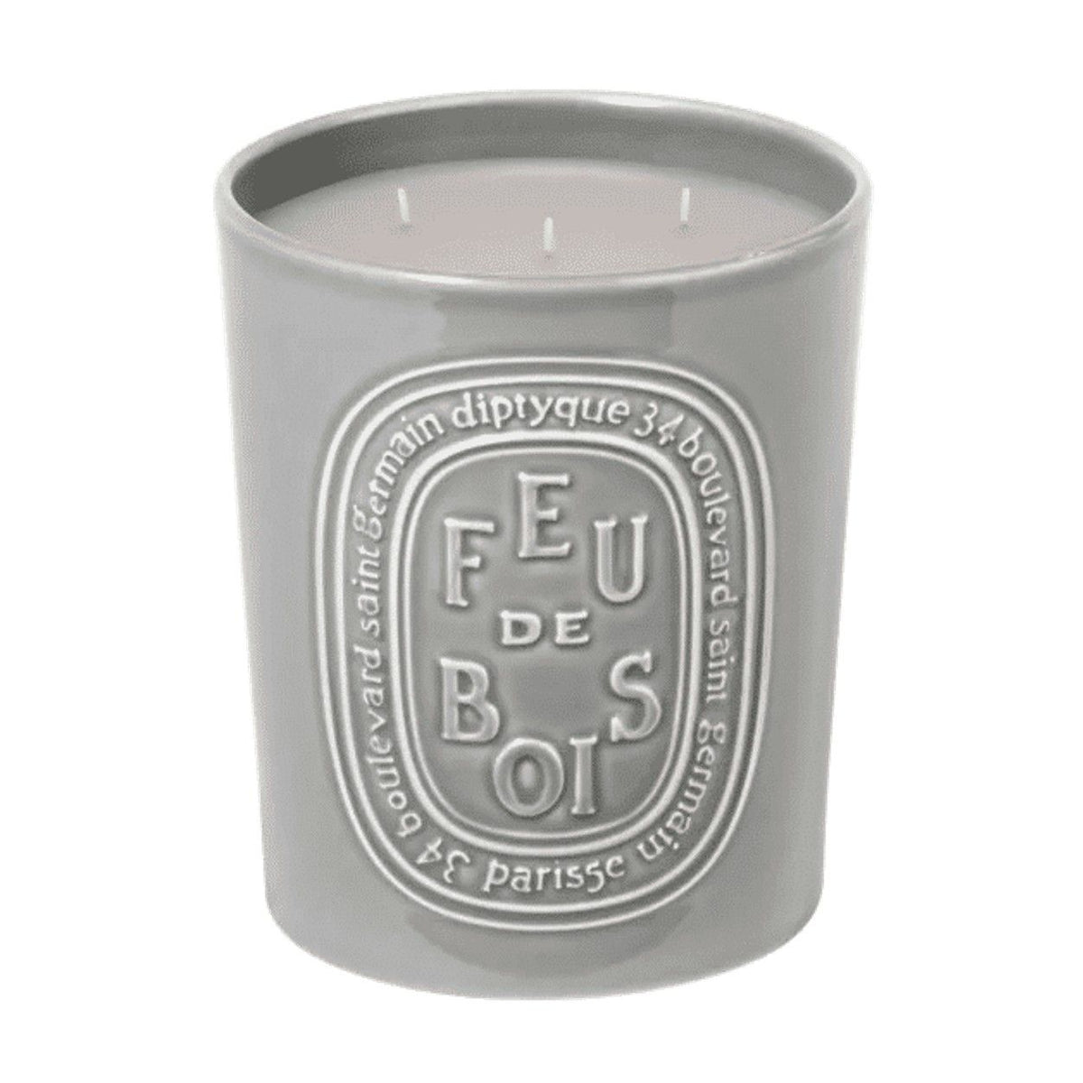 A grey three-wick Diptyque Feu de Bois (Wood Fire) Candle in a ceramic jar with an oval embossed label, evoking the scent of a winter fireplace.
