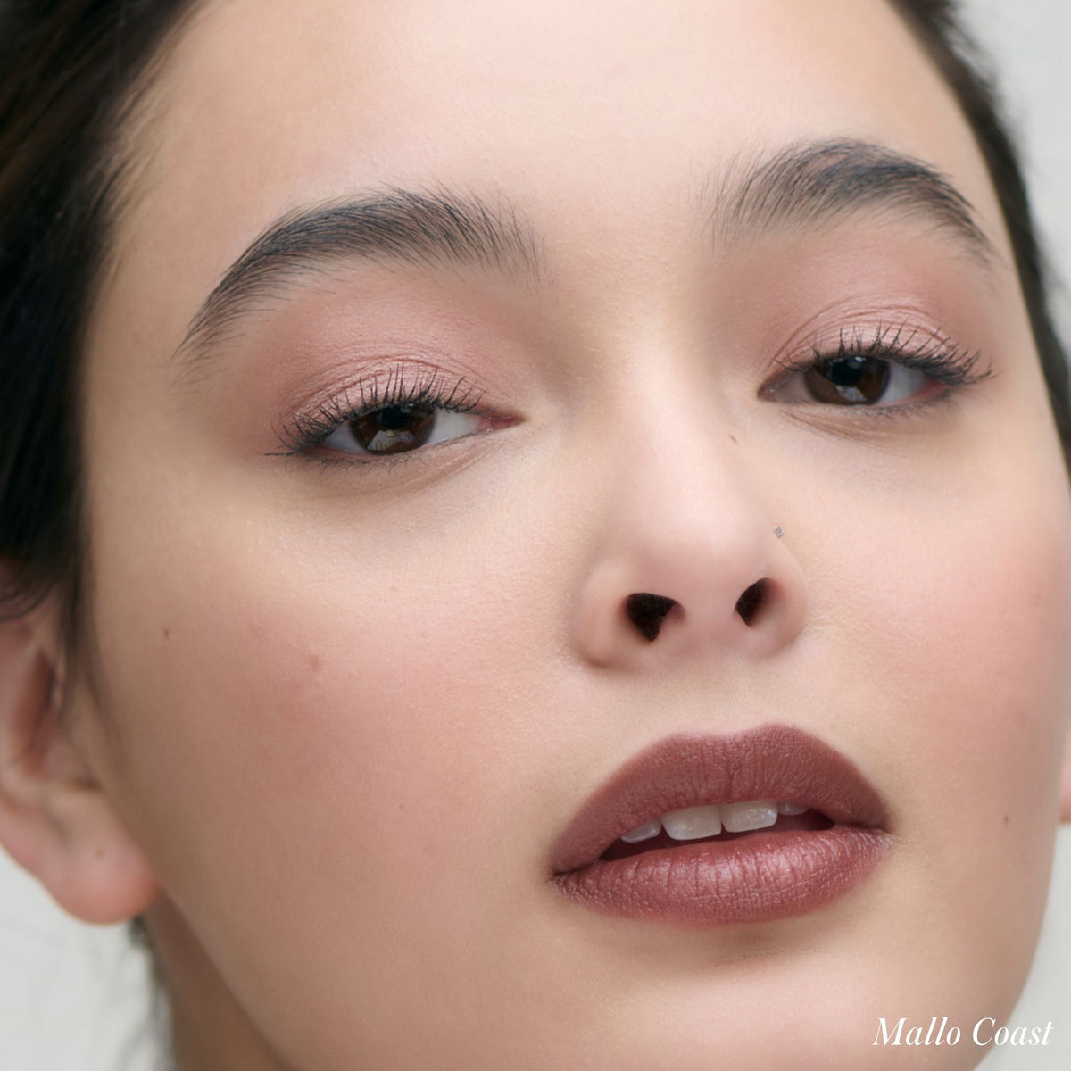 Close-up of a person wearing Cashmere Matte Eyelights creaseproof, matte cream eyeshadow and dark mauve lipstick.