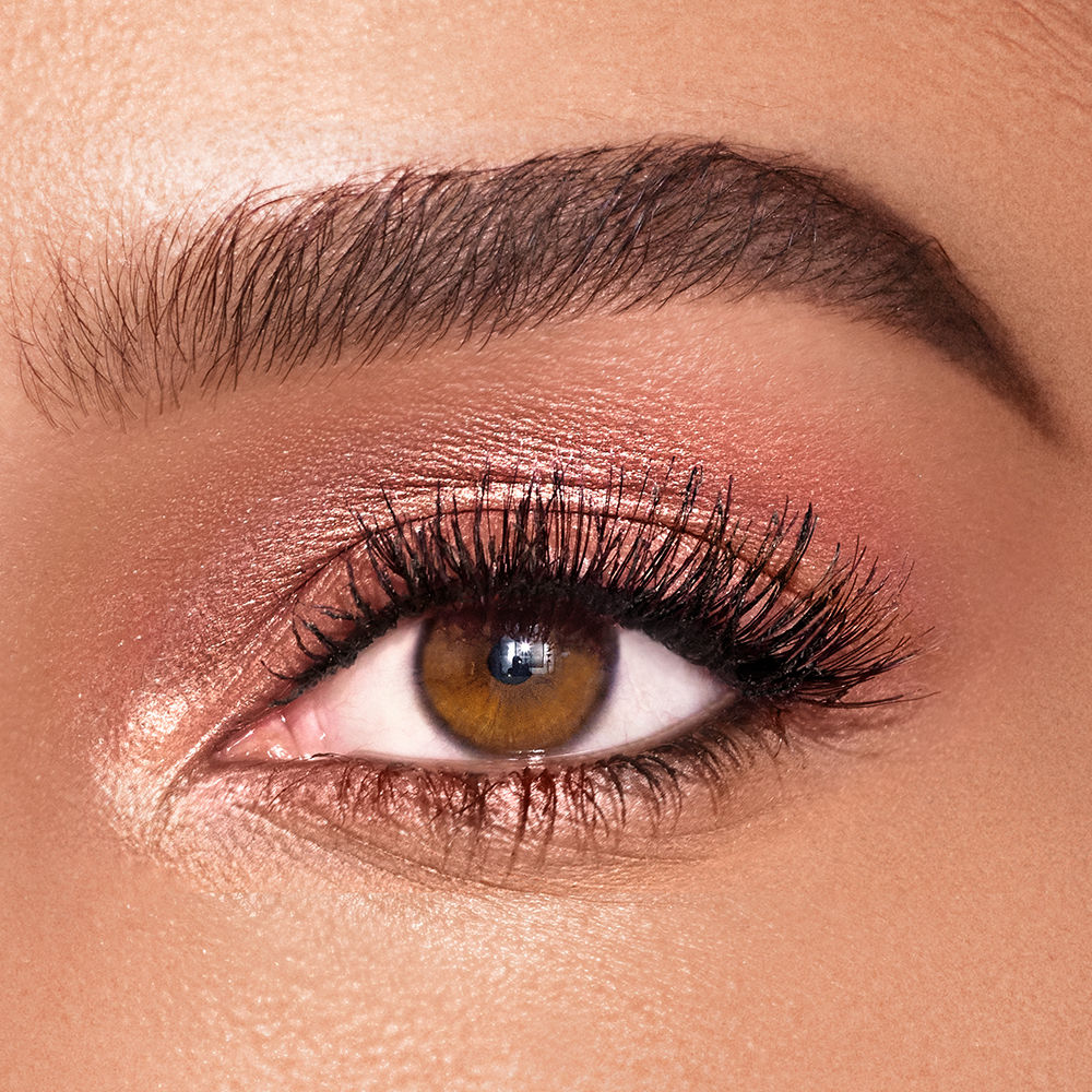 Close-up of a brown eye wearing Charlotte Tilbury Eyes To Mesmerise in shimmering rose gold, a long-lasting, non-creasing cream eyeshadow.