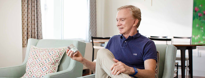 Dr. Gregory Bayes sitting on chair holding product