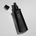 Black plastic Oribe Foundation Mist Priming Spray bottle with a removed cap, featuring gold text that reads Foundation Mist and brume de base.