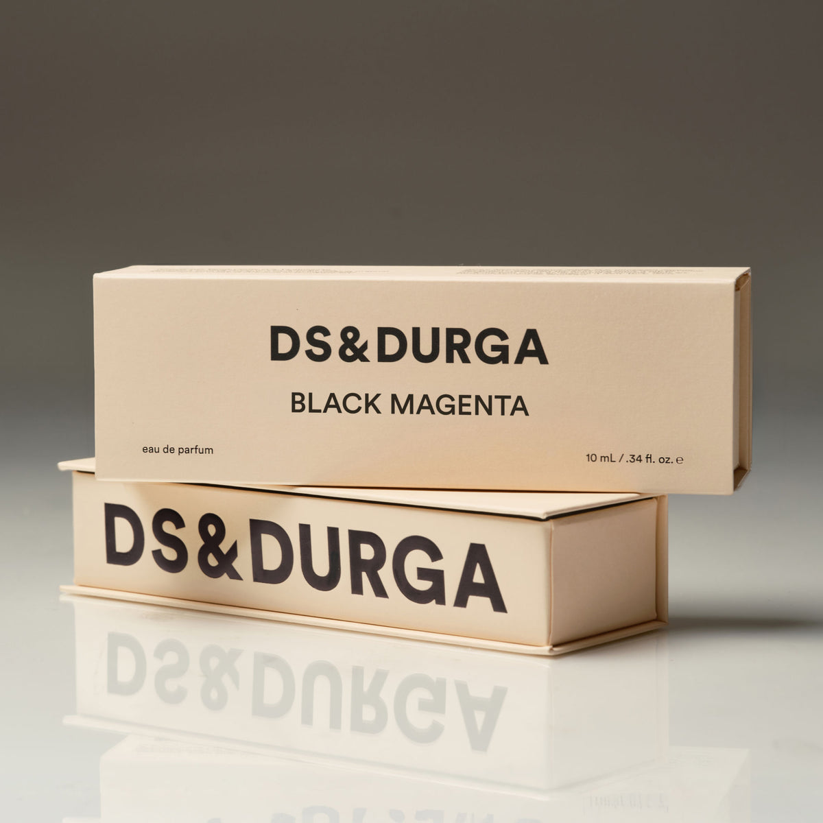 Two stacked light beige rectangular Black Magenta Eau de Parfum boxes with black lettering.