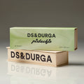 Two rectangular boxes of D.S. & Durga Pistachio Eau de Parfum stacked on a reflective surface, with the light green pistachio box on top and the cream-colored box showing brand text on the bottom.