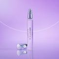 A tall, thin glass spray bottle of 11 11 Lychee Eau de Parfum with its silver cap resting on the surface next to it.