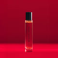 A cylindrical glass rollerball of Heretic Scandalwood Eau de Parfum with a black cap, featuring the scent name on the label.