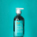 A bottle of Moroccanoil Hydrating Styling Cream for smoothing fly-aways sits behind a condensation-covered surface.