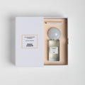 A rectangular Sana Jardin Sandalwood Temple Eau de Parfum bottle with a large, round grey cap sits inside an open white gift box, with the product name and brand printed on the box cover and the bottle label.