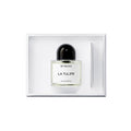 A glass bottle of Byredo La Tulipe Eau de Parfum with a black cap sits in a white box next to a thin applicator stick.