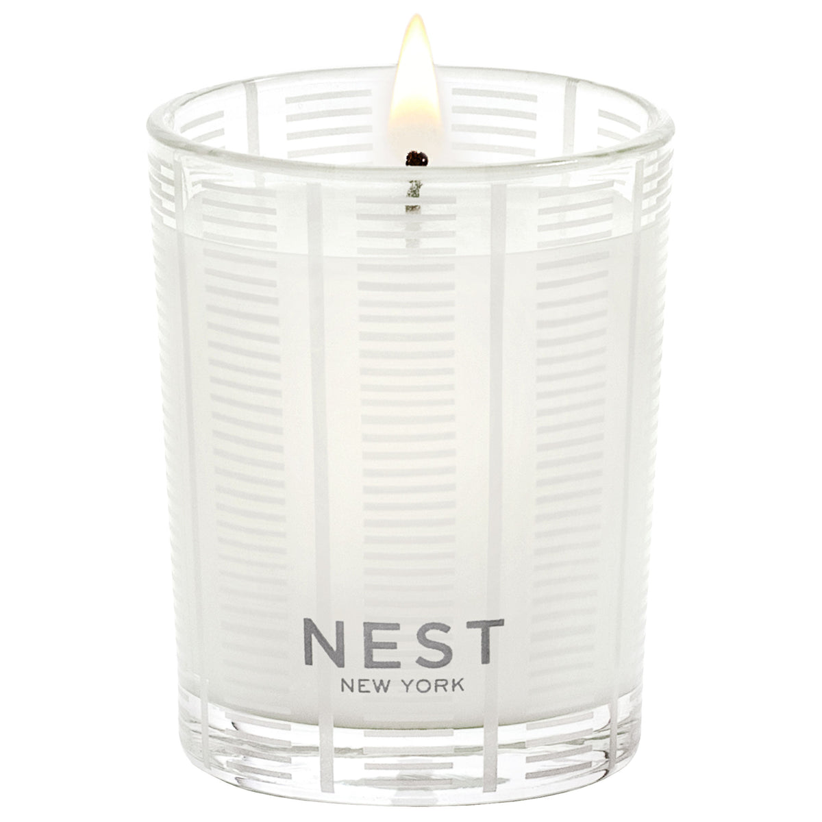 A lit Nest New York Forest Rain Candle in a clear glass vessel with a striped pattern, capturing the essence of dewy fig leaves.