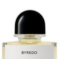Close-up of a clear glass Byredo Future Memories Eau de Parfum bottle with a black domed cap and a white label, evoking textured vanilla and powdery iris.