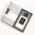 A rectangular bottle of MYTH Eau de Parfum with a black cap and a black label with gold text rests inside an open gift box containing notes of liquid musks and jasmine petals.