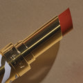 A gold tube of Phyto-Rouge Shine lipstick with an extended coral-toned bullet that offers a balm-like sensation.