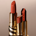 Three Phyto-Rouge Shine lipsticks in metallic gold tubes with animal print patterns, featuring various shades of intense lipstick in a balm-like sensation.