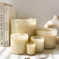 Four graduated Lafco Chamomile Lavender candles arranged next to a stack of books and a small matchbox.