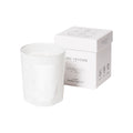 A white Trudon Giambattista Valli Candle in an embossed glass vessel next to its matching white square box.
