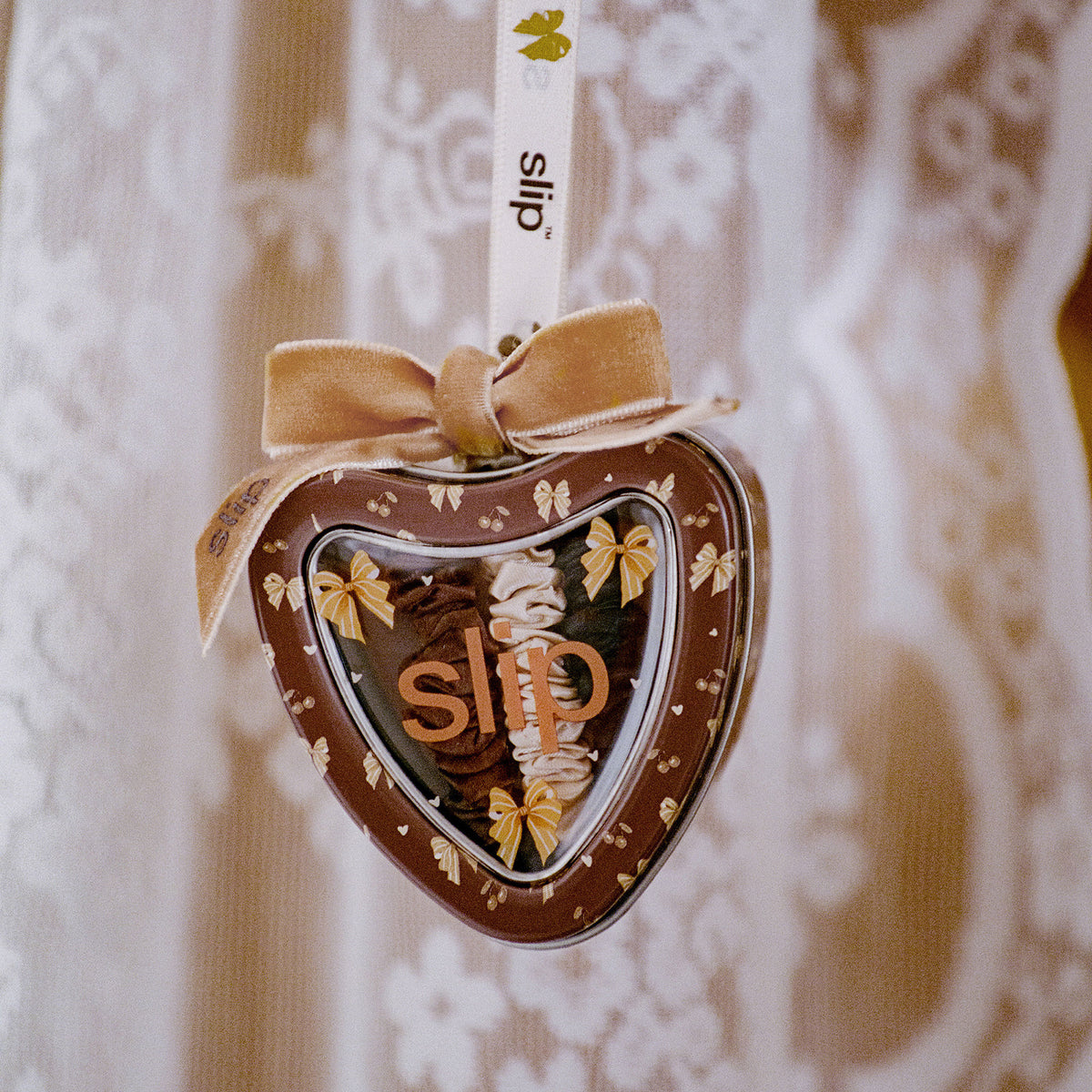 Pure Silk Skinny Scrunchie Trio Ornament heart-shaped tin containing three anti-crease fabric scrunchies, topped with a ribbon bow.