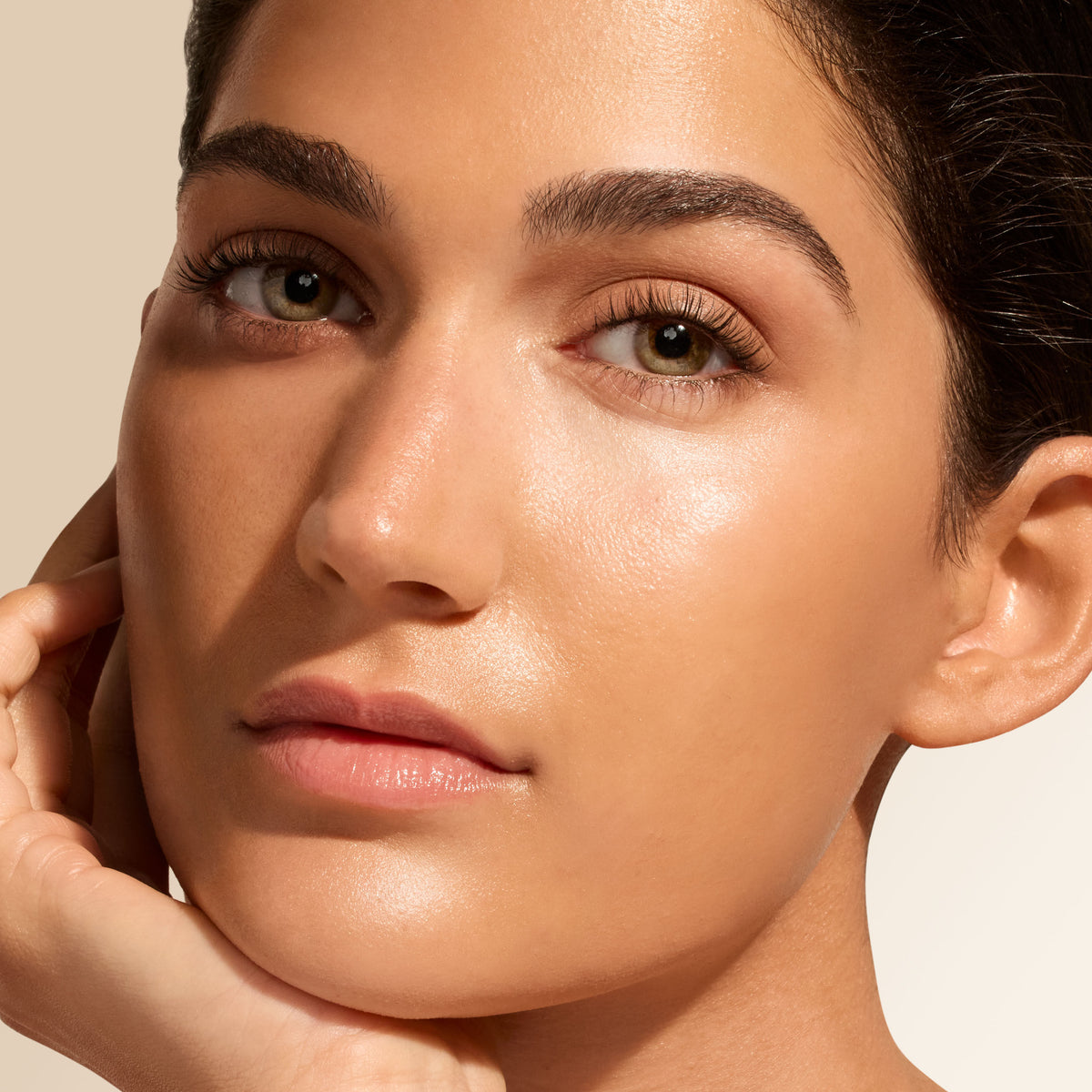 Close-up of a person with glowing, dewy skin enhanced by Jane Iredale Glow Fixation SPF 40 Sheer Tint Skin Enhancer with Squalane & Niacinamide, resting their chin on their hand.