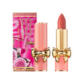 A pink SatinAllure Lipstick tube with a gold bow accent standing next to its matching rose-patterned box, offering a weightless silky smooth lip color.