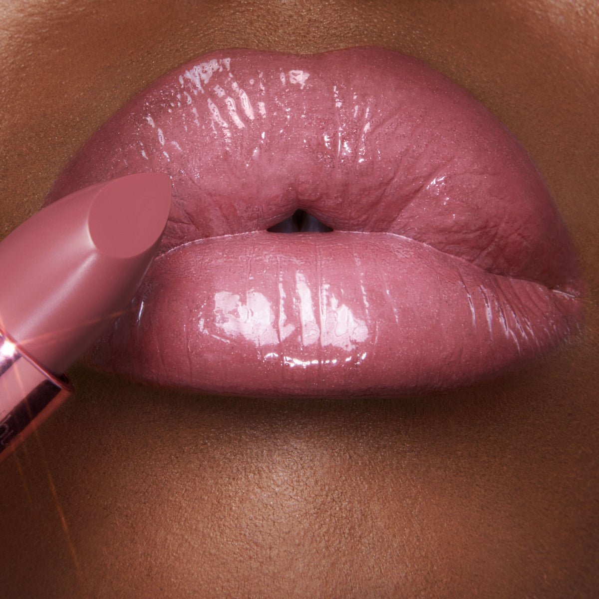Close-up of glossy, muted pink K.I.S.S.I.N.G. Lipstick applied to lips, next to the lipstick bullet.