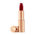 A tube of deep red Charlotte Tilbury Matte Revolution lipstick with its metallic cap resting beside the base.